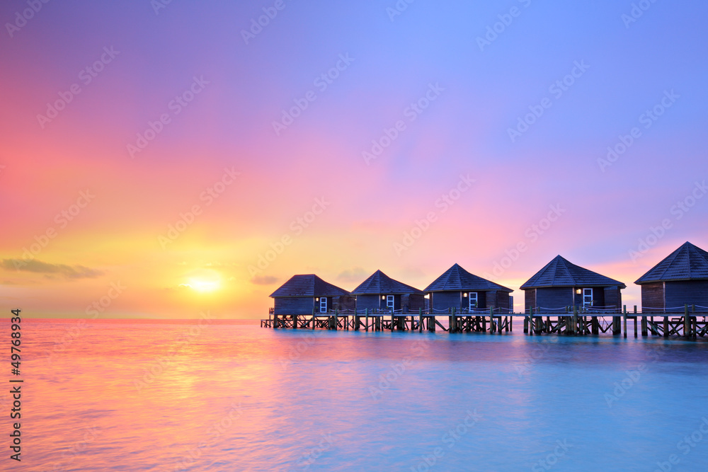 Obraz premium Sunset on Maldives island, water villas resort