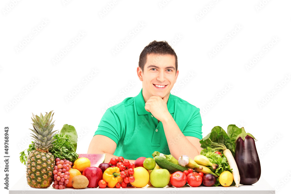 Young man posing with a pile of fruits and vegetables Young man posing with a pile of fruits and vegetables