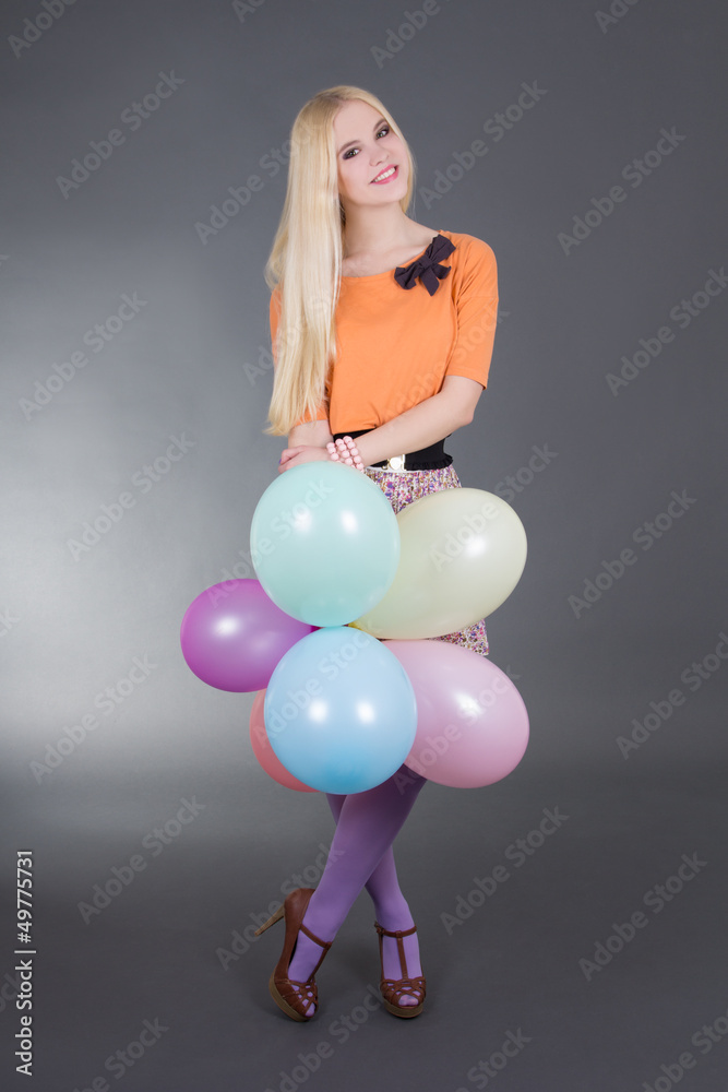 Fototapeta premium young attractive woman holding balloons over grey