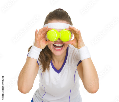 Happy tennis player holding balls in front of eyes © Alliance