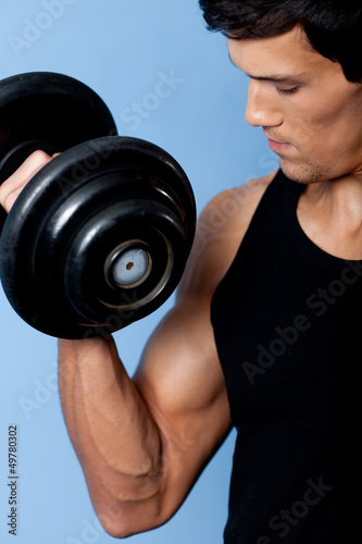 Handsome muscular man uses his dumbbell