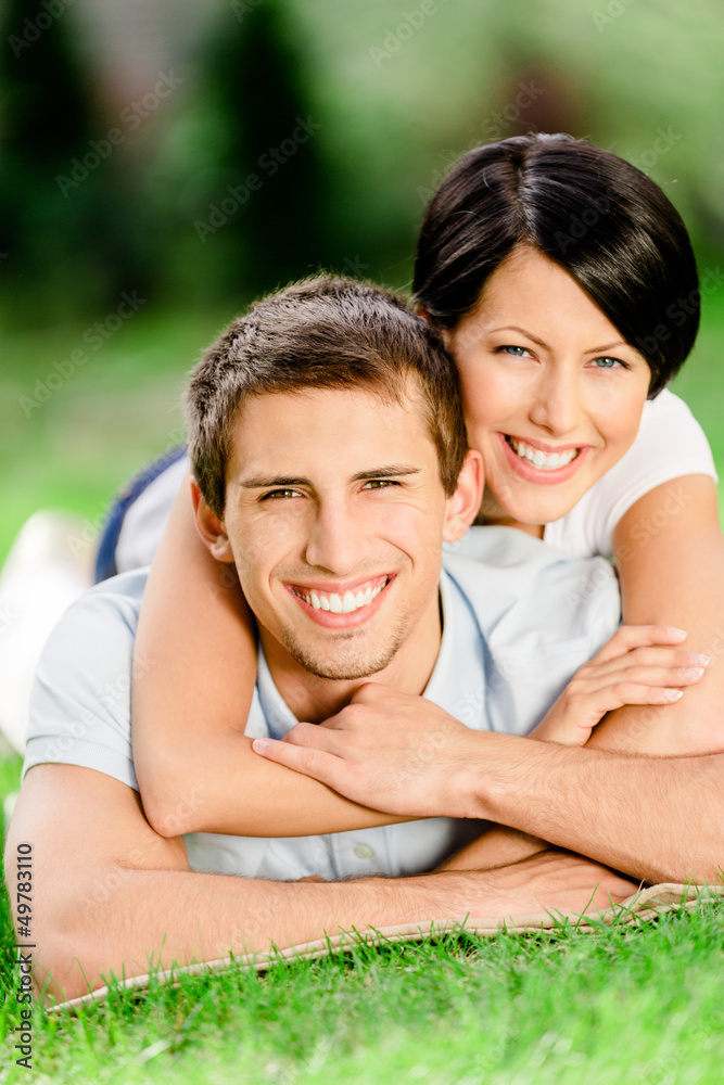 Couple lying on the green grass embraces each other Couple lying on the green grass embraces each other