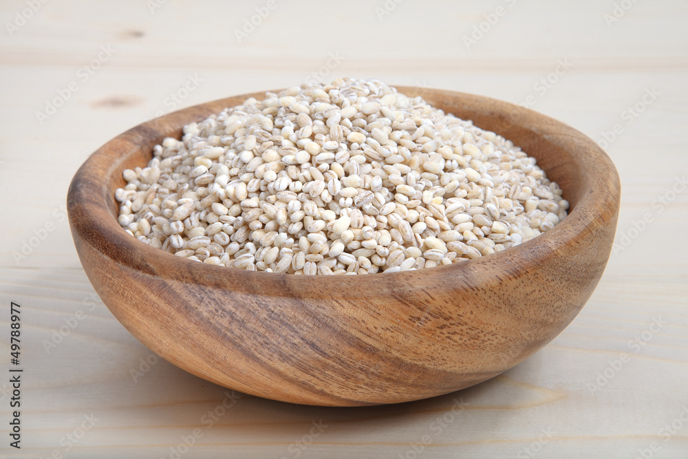 a bowl of pearl barley on wooden surface a bowl of pearl barley on wooden surface