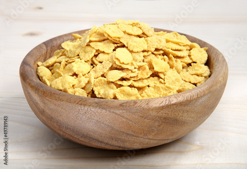a bowl of cornflakes on wooden surface