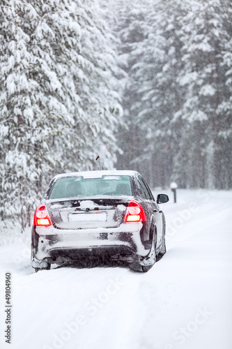 Black car standing on country road in wintry northern forest