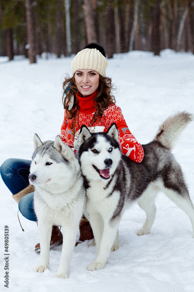 Happy woman playing with siberian husky dogs in winter forest Happy woman playing with siberian husky dogs in winter forest
