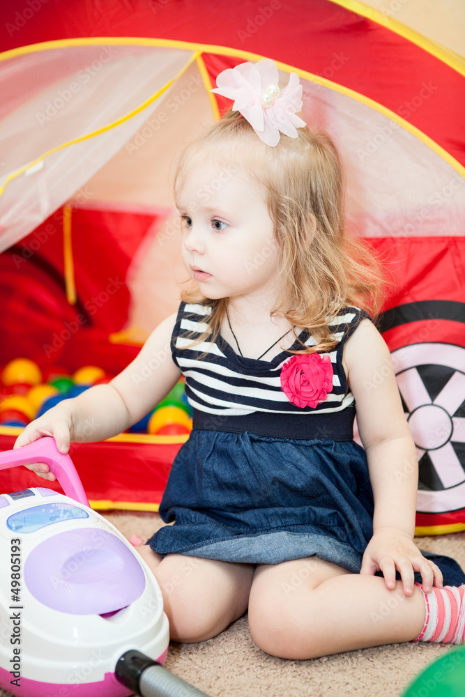 Happy little child playing with vacuum cleaner toy in room Happy little child playing with vacuum cleaner toy in room