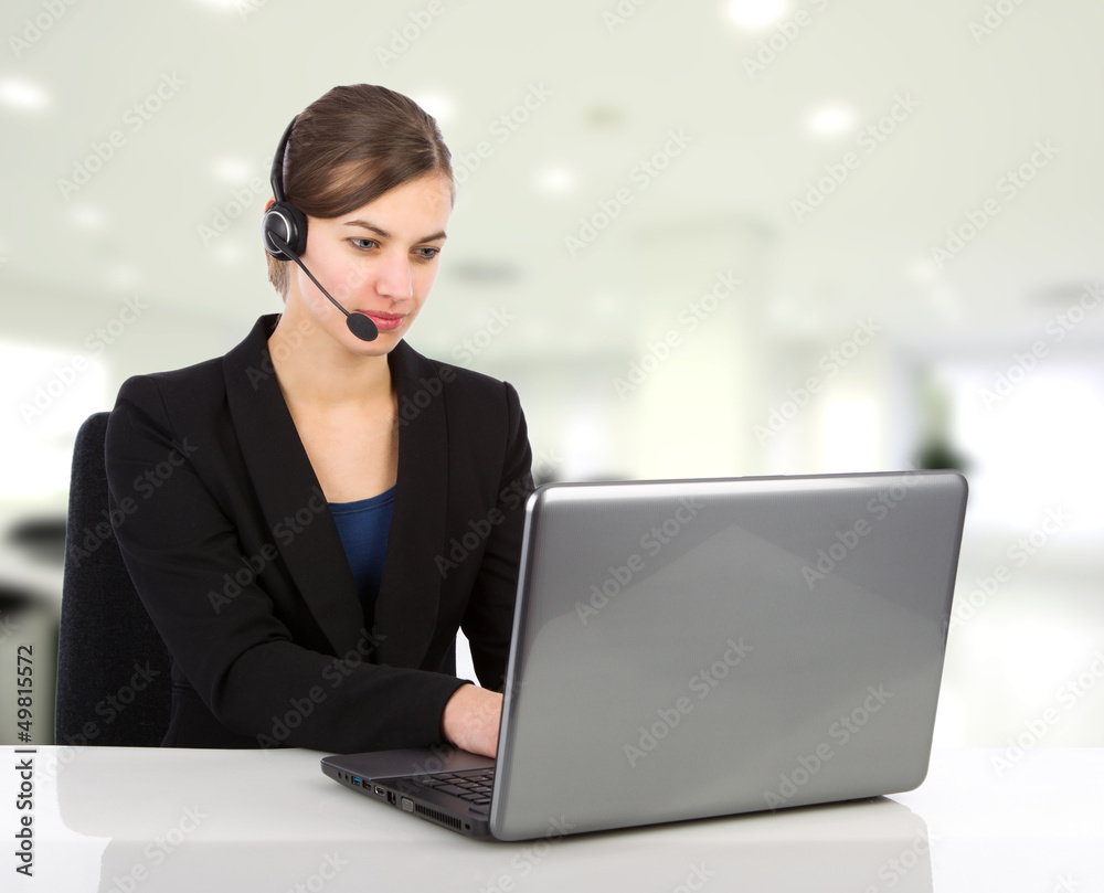 Attractive business woman with headset working on a laptop Attractive business woman with headset working on a laptop