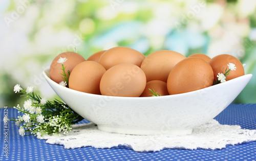 Eggs in white bowl on blue tablecloth close-up