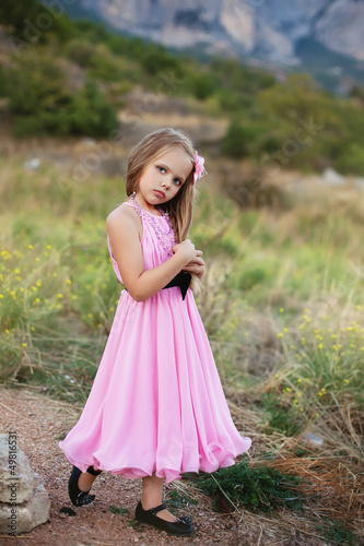 Beautiful little girl in a pink dress walking