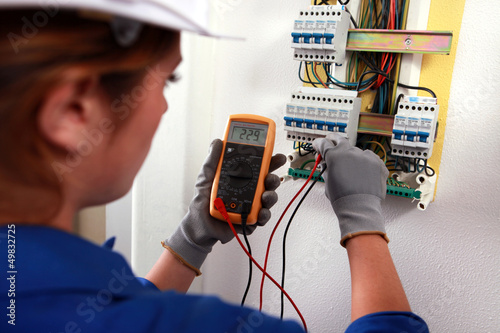 Female electrician checking a fusebox photo