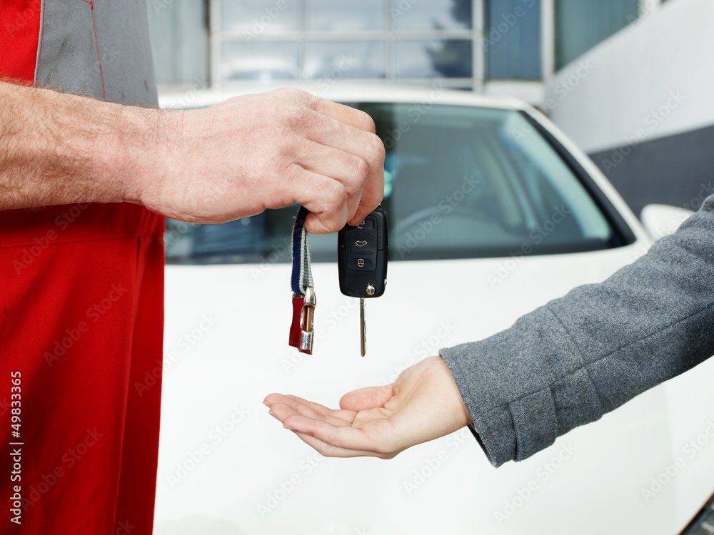 Key delivery between customer and mechanic in front of new car