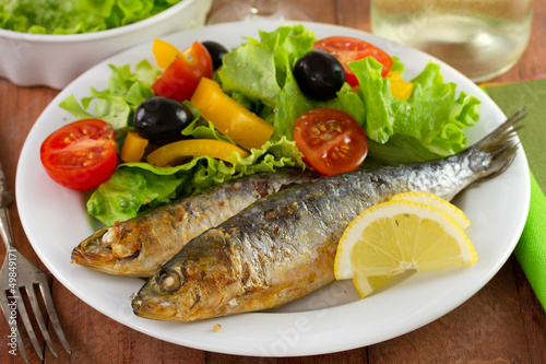 fried sardines with salad and lemon on the plate