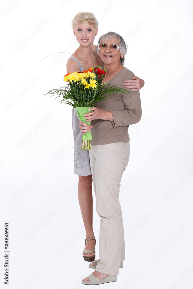 Woman giving her mother flowers Woman giving her mother flowers