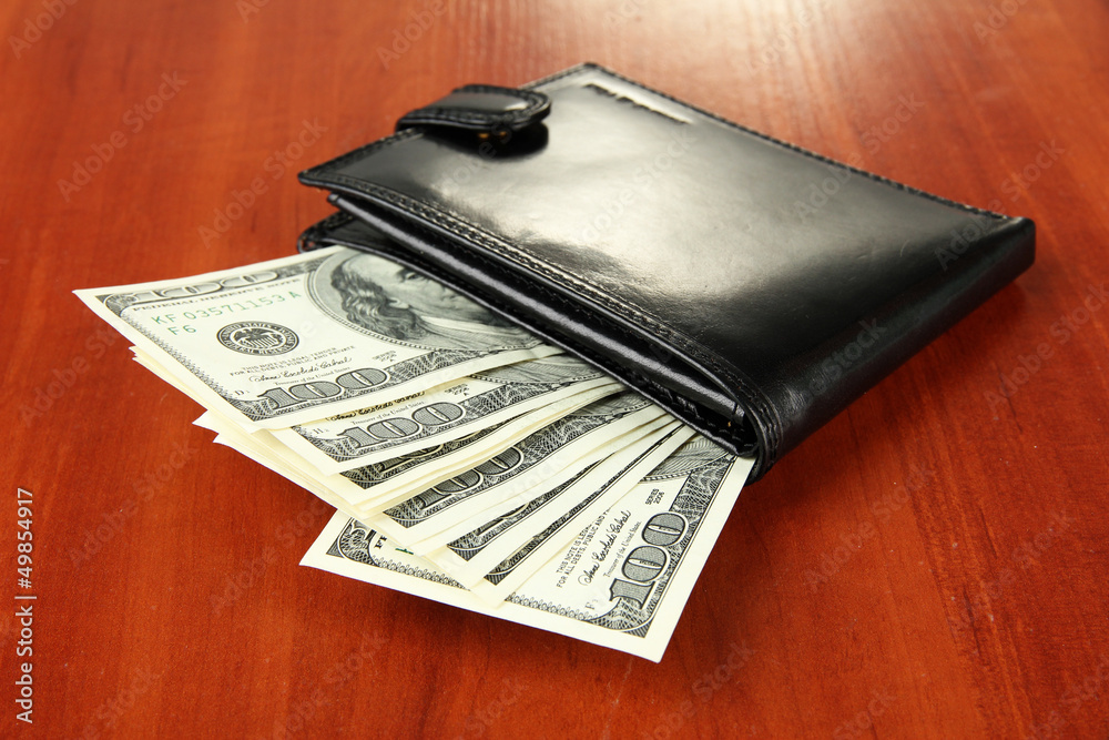 Wallet with hundred dollar banknotes, on wooden background Wallet with hundred dollar banknotes, on wooden background