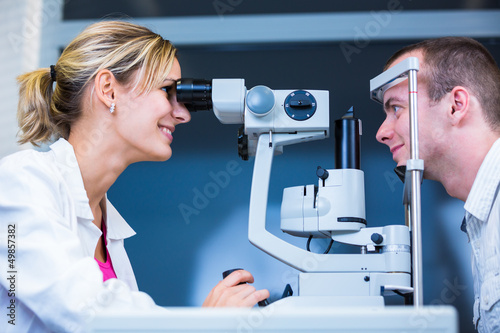 Optometry concept - handsome young man having his eyes examined