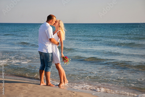 Tableau sur toile Couple on summer sea beach hug one another and kissing