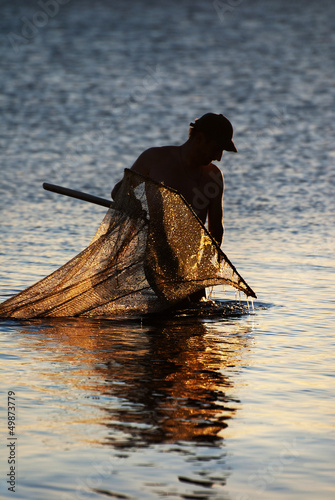 Fisherman with the landing net at sunset sea way