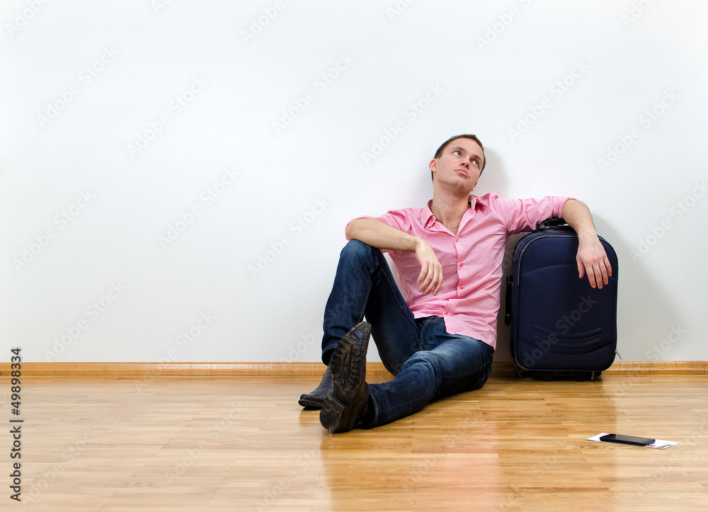 Young man sitting on the floor near suitcase Young man sitting on the floor near suitcase