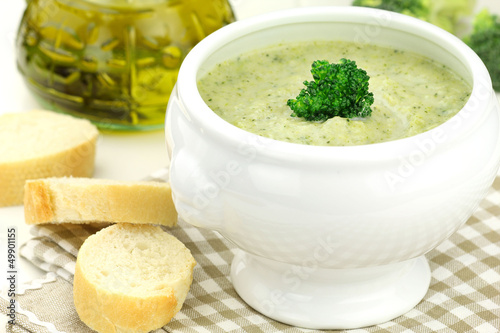 Creamy broccoli soup in a white bowl served with some bread