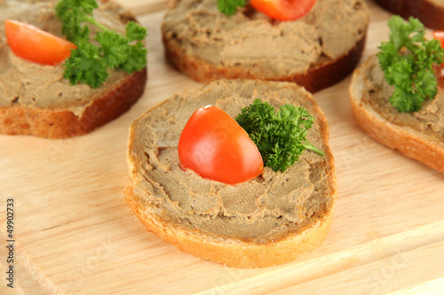 Fresh pate on bread on wooden board, close up