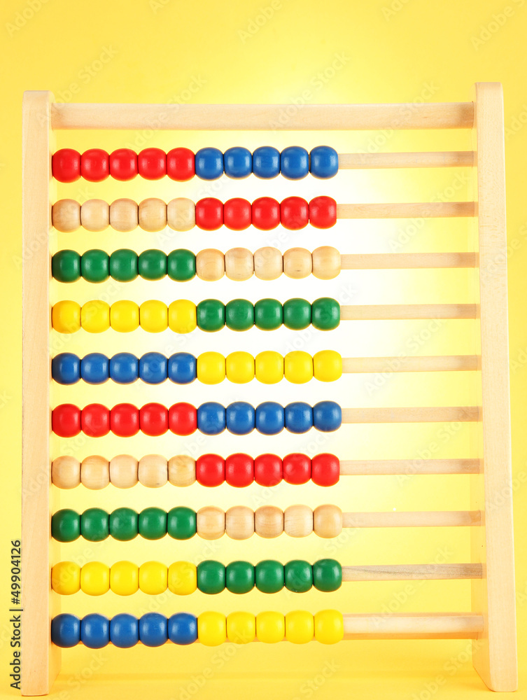Bright wooden toy abacus, on yellow background Bright wooden toy abacus, on yellow background