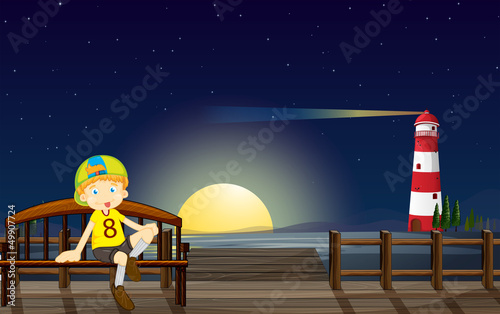 A boy sitting at the bench in the middle of the night
