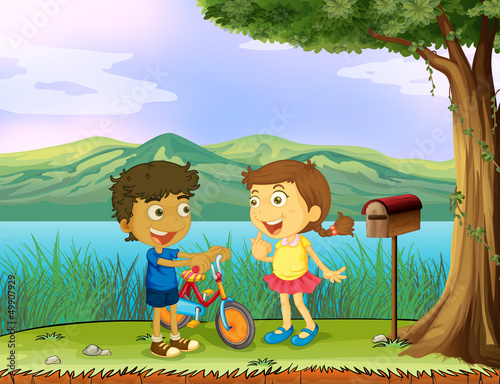 A young boy holding a bike and a girl near a wooden mailbox