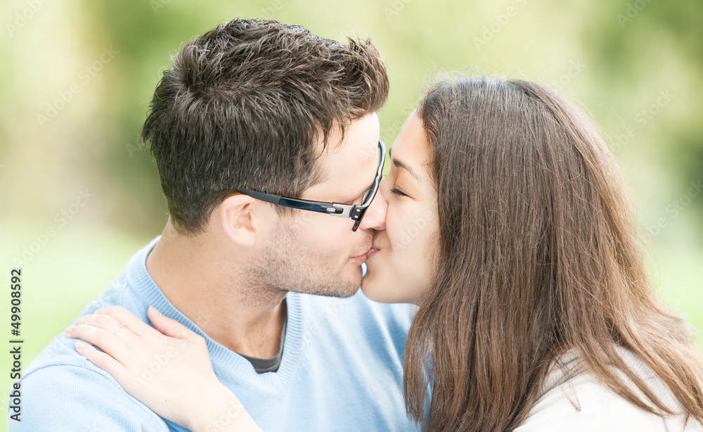Pretty woman and man in glasses kissing in park. Pretty woman and man in glasses kissing in park.