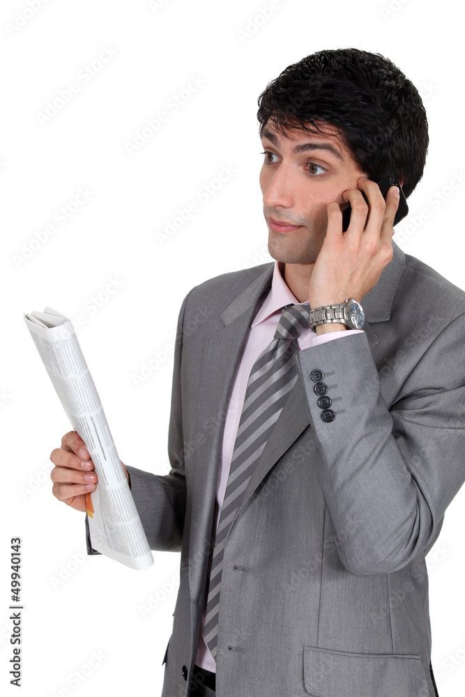Businessman taking on phone and holding newspaper Businessman taking on phone and holding newspaper