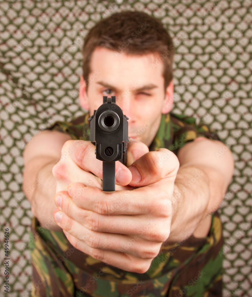 Soldier in camouflage vest is holding a gun Soldier in camouflage vest is holding a gun