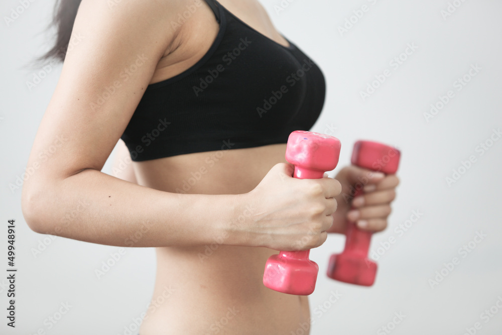 The girl in sportswear is engaged in the gym with dumbbells The girl in sportswear is engaged in the gym with dumbbells
