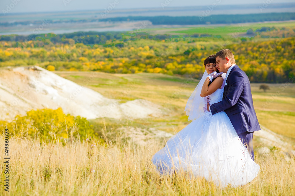 Russia bride and groom outdoor standing in a yellow field hug, p