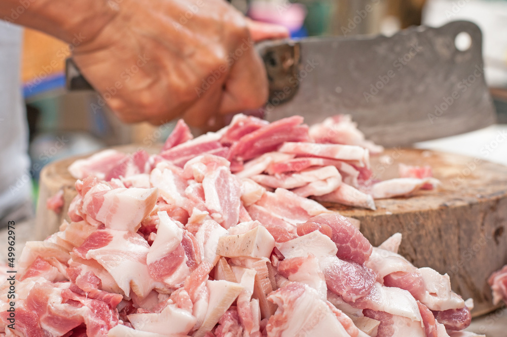 Hands cutting pork meat