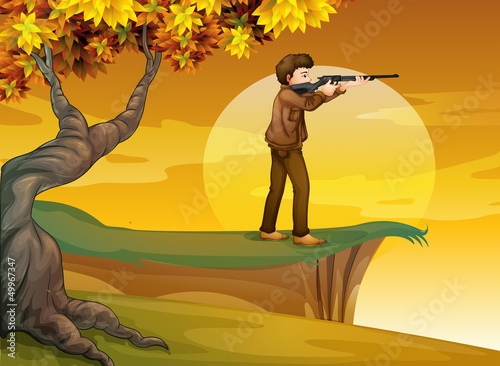 A boy holding a gun near the tree