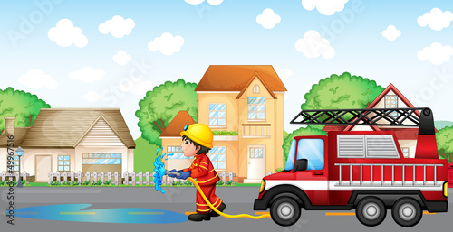 A fireman holding a hose with a fire truck at the back