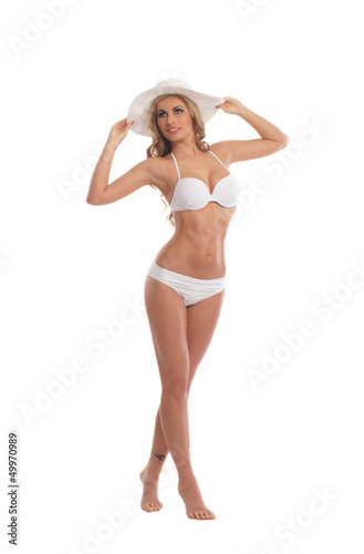 A young and fit woman posing in a white swimsuit and a hat