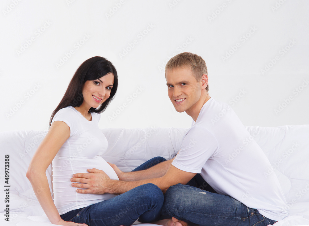 A young Caucasian couple on a white sofa waiting for the baby A young Caucasian couple on a white sofa waiting for the baby