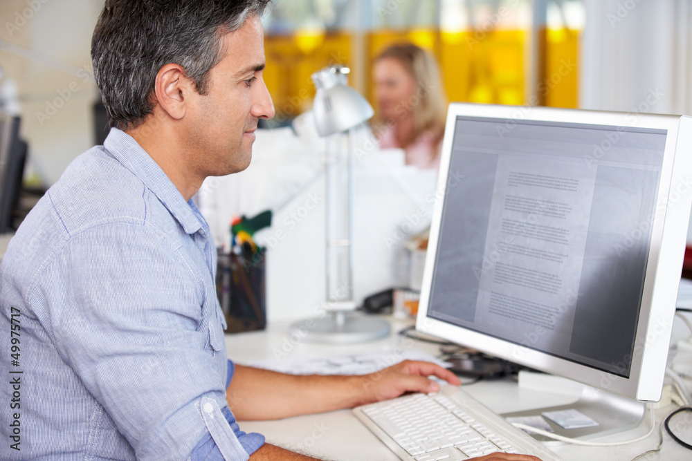 Fototapeta premium Man Working At Desk In Busy Creative Office