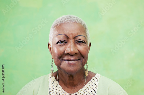Obraz na plátně Portrait of senior black woman smiling at camera on green backgr