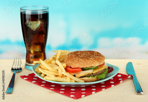 Tasty cheeseburger with fried potatoes and cold drink,