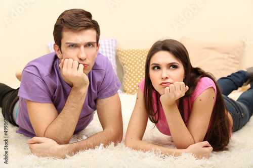 Young couple lying on carpet at home