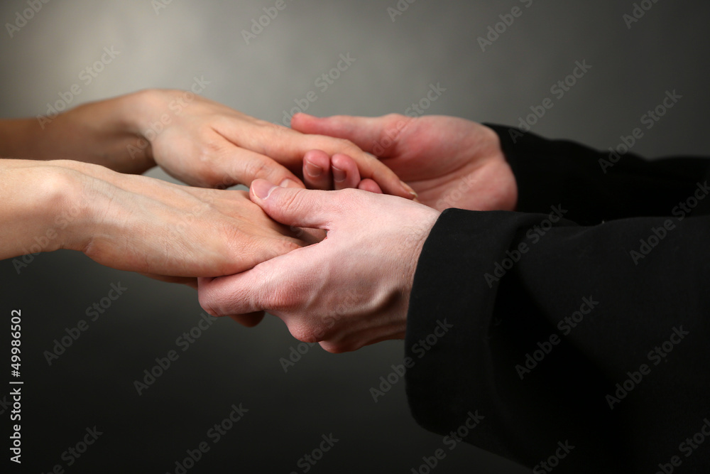Priest holding woman hands, on black background Priest holding woman hands, on black background