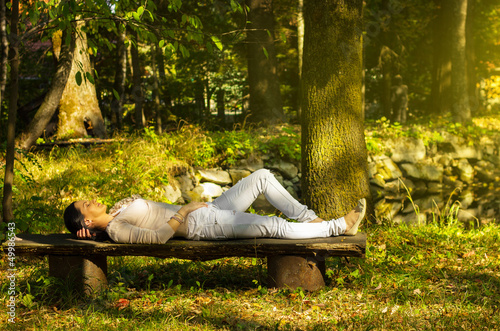 Woman with eyes closed relaxing on a bench in nature