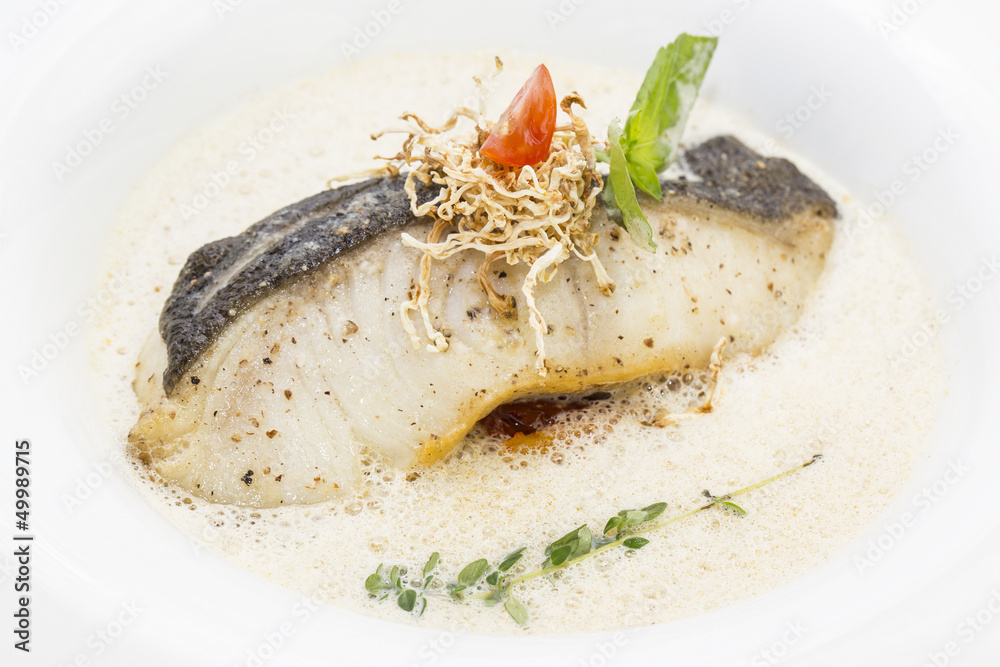 baked cod under tender sauce on a plate in a restaurant baked cod under tender sauce on a plate in a restaurant