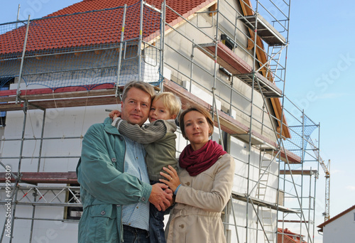 Junge Familie vor Eigenheim