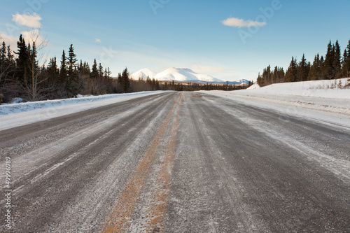 Winter on country road in taiga and snowy mountain
