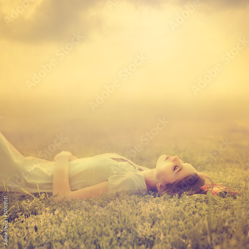 beautiful young girl dreams of lying on a magic meadow in spring