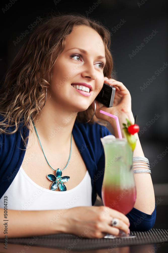 Happy young woman with cocktail calling on the phone Happy young woman with cocktail calling on the phone