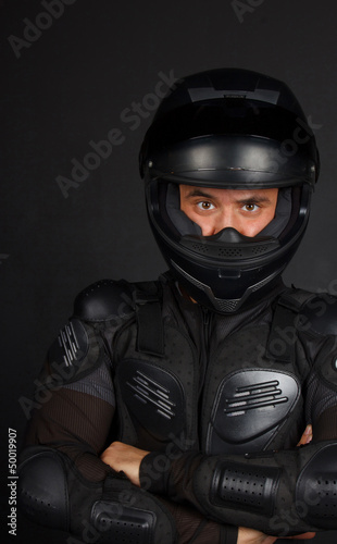 Self confident biker with a crossed hands in a dark background
